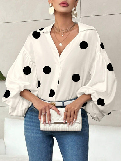 Woman wearing an apricot polka dot V-neck long-sleeve top with bubble sleeves and blue jeans.