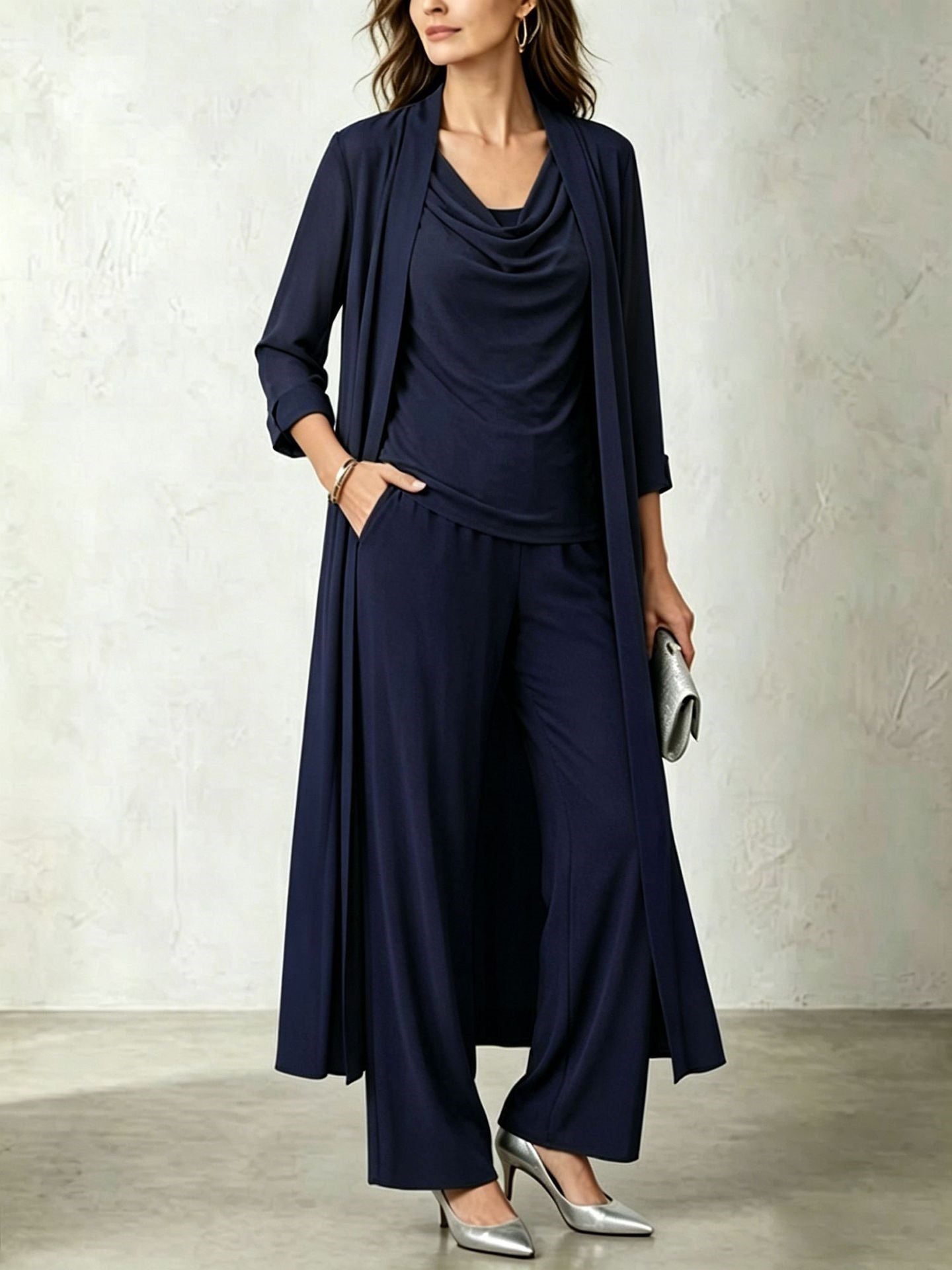 Model wearing a dark navy blue three-piece cardigan and wide-leg pant set paired with metallic silver pumps and a silver clutch