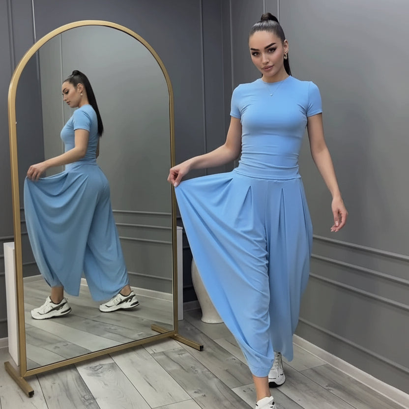 Model with a high ponytail posing in front of a mirror wearing a sky blue short-sleeve fitted top and volume harem pants paired with white chunky sneakers.