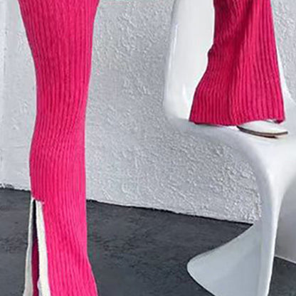 Close-up of vibrant pink knit trousers featuring a high side slit at the ankle, worn while sitting on a white modern chair.