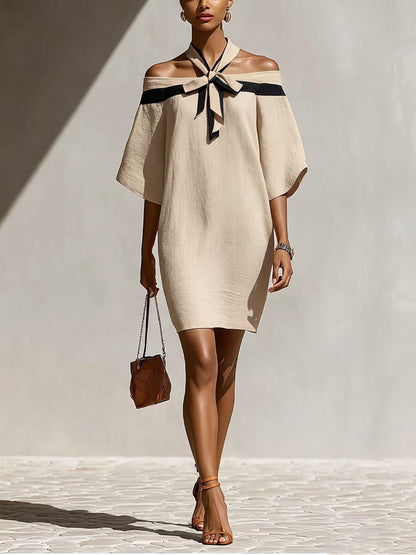 Woman wearing an apricot beige off-the-shoulder A-line mini dress with a contrasting black bow collar