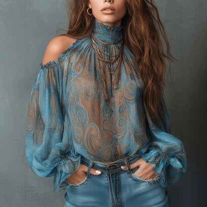Front view of a woman wearing a peacock green retro cashew paisley print off-shoulder blouse with a high ruffled mock neck and dramatic lantern sleeves, styled with blue denim jeans.