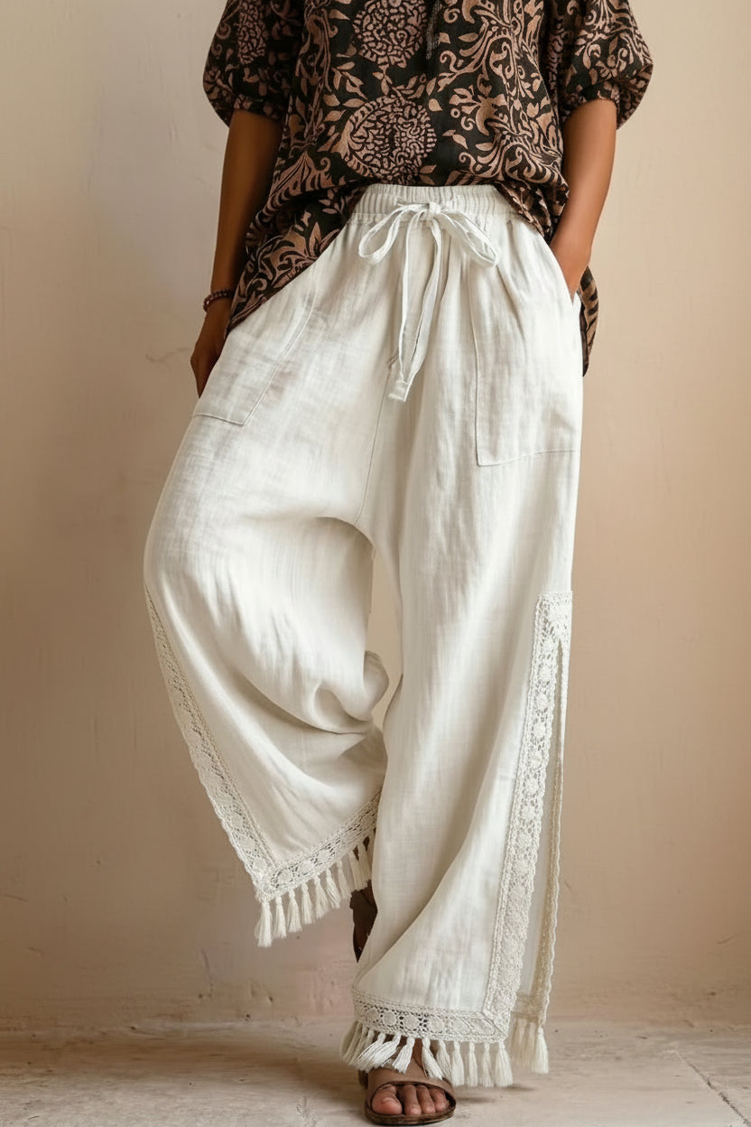 Women's bohemian lace tassel wide-leg pants in white, featuring a drawstring waist, side slit with fringe trim, and a flowing silhouette.