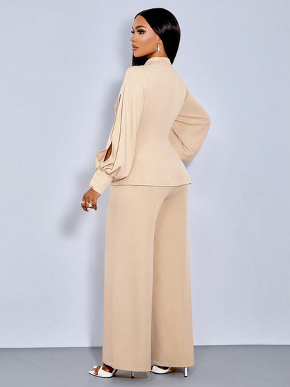Rear three-quarter view of a woman wearing an apricot beige suit set featuring a high-neck blazer with long bishop slit sleeves and matching wide-leg pants.