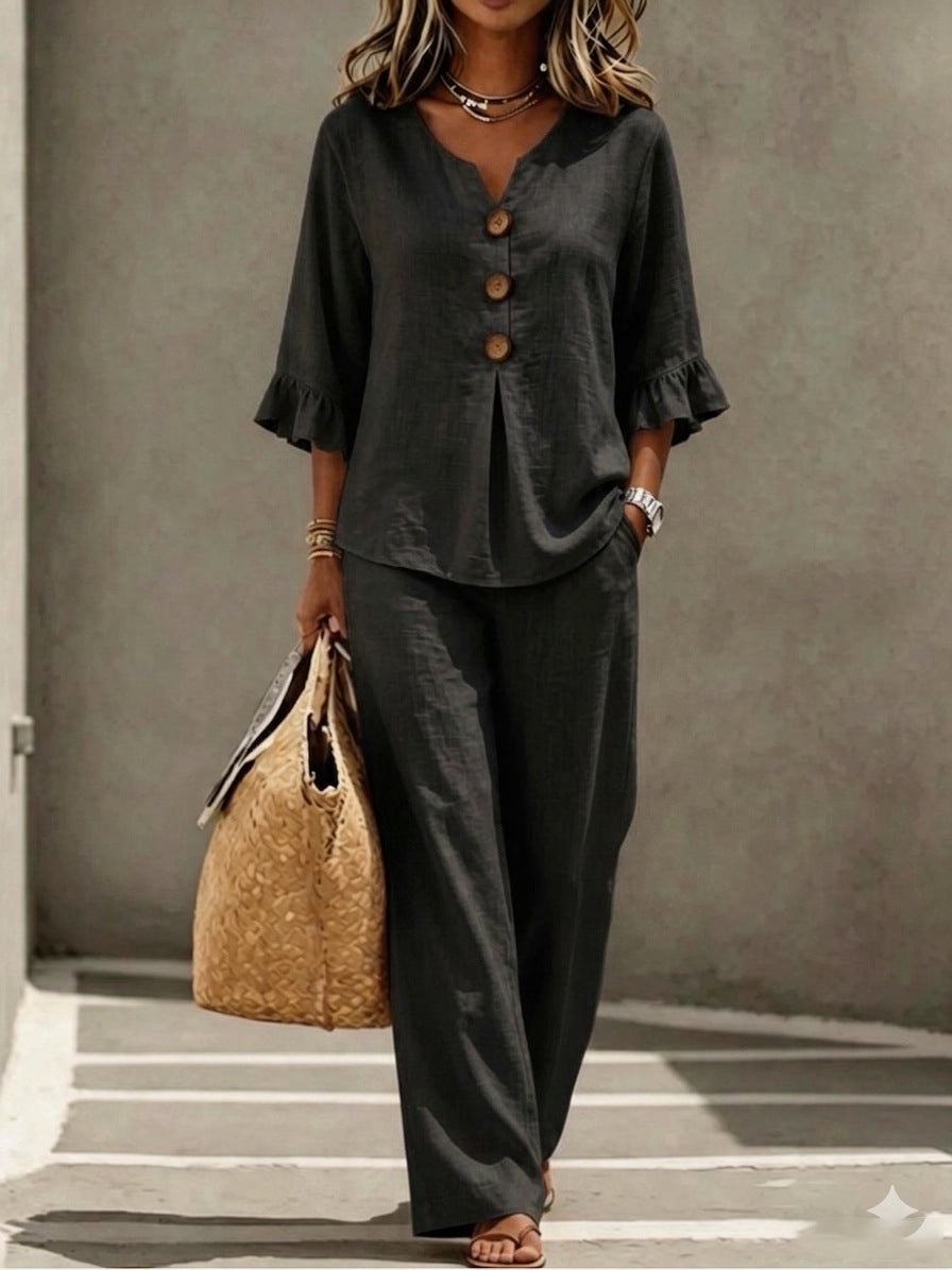 Women's two-piece set in black, featuring a button-down V-neck ruffle top, matching relaxed-fit pants, and three-quarter sleeves.
