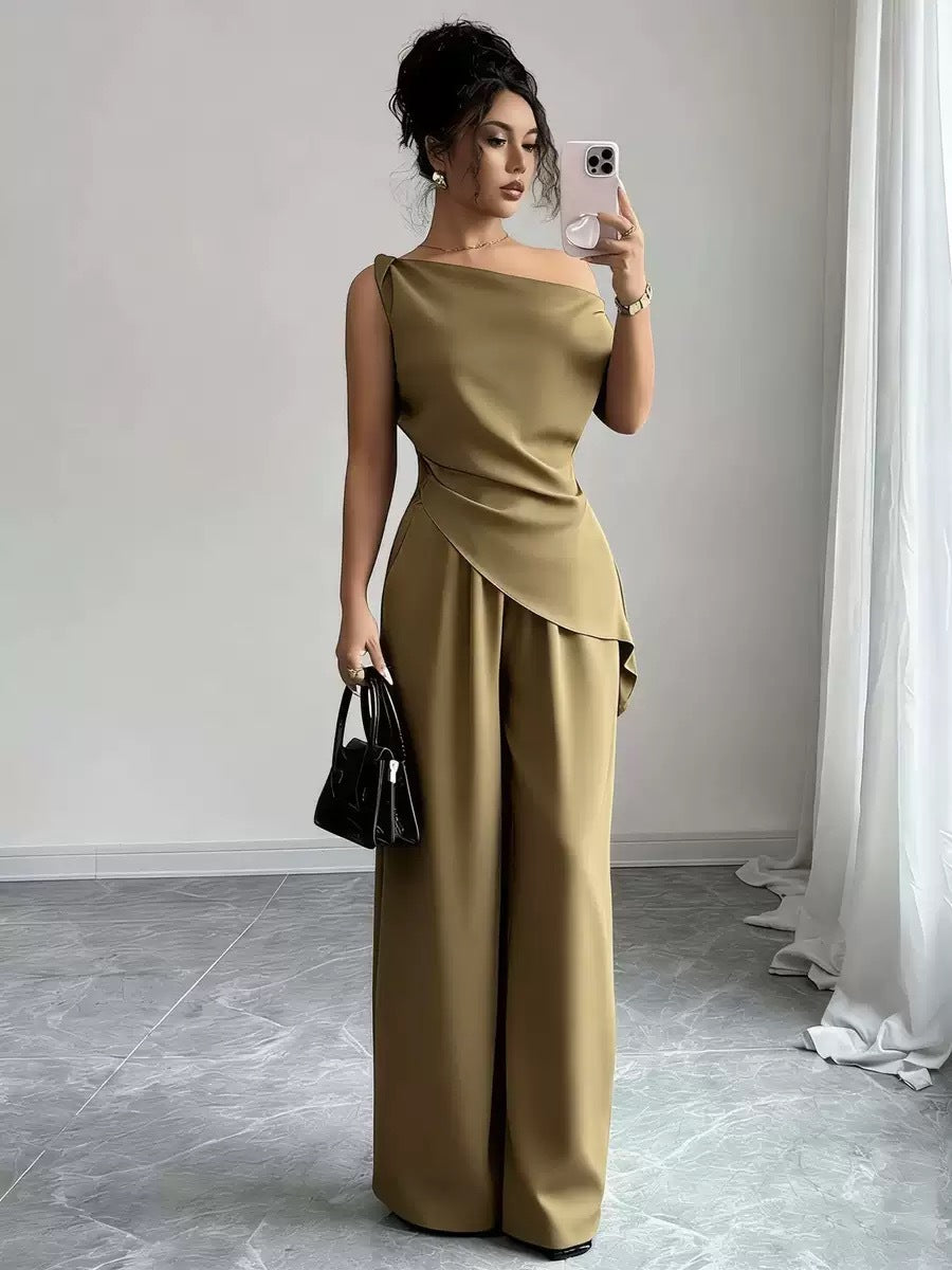 Woman taking a mirror selfie wearing an olive green casual two piece set featuring a draped off-the-shoulder top with a diagonal front fold and matching high-waisted wide-leg pants, holding a black handbag and smartphone.
