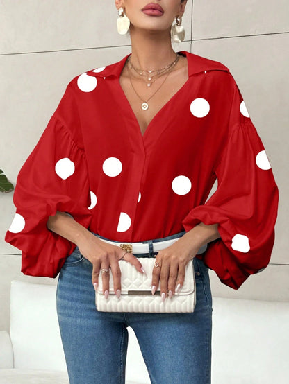 Woman wearing a bright red polka dot V-neck long-sleeve top with bubble sleeves and blue jeans