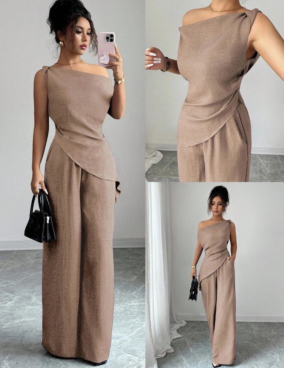 Woman taking a mirror selfie wearing a camel brown casual two-piece set featuring a draped off-the-shoulder top with a diagonal front fold and matching high-waisted wide-leg pants, holding a black handbag and smartphone.
