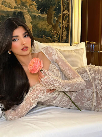 Ivory white long-sleeve lace shawl mermaid maxi dress set featuring a square neckline, backless design, and floral lace texture, shown as a model lies elegantly on a bed holding a peach rose.