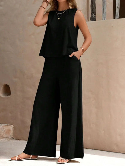 Front view of model wearing a black sleeveless round neck top and high-waisted wide leg pants set with sandals