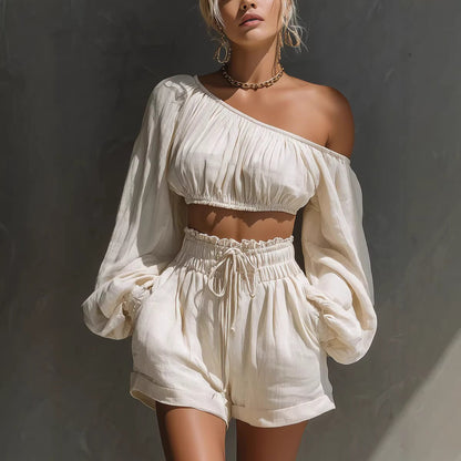 Women's one-shoulder ruched crop top and high-waist shorts set in white, featuring billowy long sleeves and a relaxed-fit drawstring waistband.