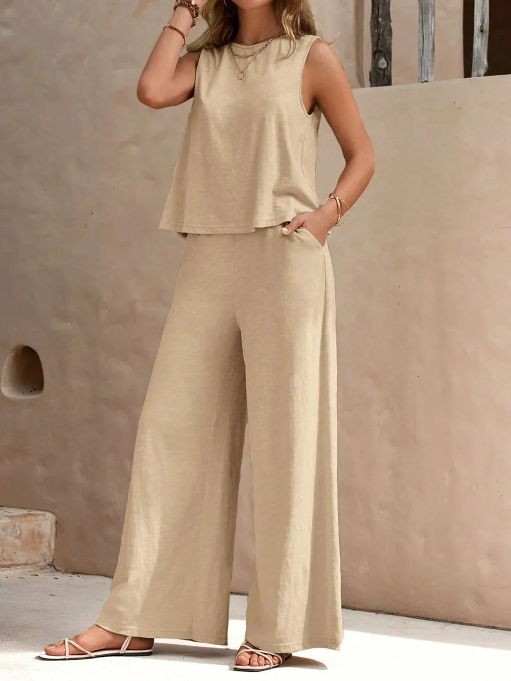 Front view of model wearing beige sleeveless round neck top and high-waisted wide leg pants set with sandals