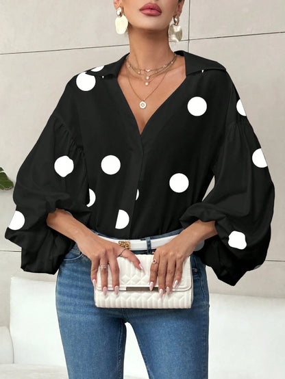Woman wearing a black polka dot V-neck long-sleeve top with bubble sleeves and blue jeans.