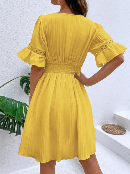 Back view of a woman wearing a bright yellow V-neck mini dress featuring short flounce sleeves with crochet lace trim, textured vertical striping, and a cinched lace waistband.