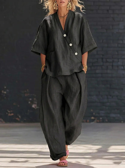 Model wearing a black V-neck short-sleeve top and matching high-waist trousers set.