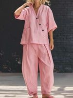 Model wearing a pink V-neck short-sleeve top and matching high-waist trousers set.