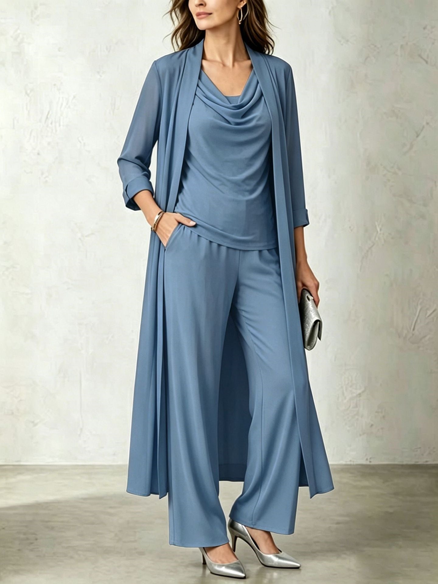 Model wearing a dust blue three-piece cardigan and wide-leg pant set paired with metallic silver pointy-toe pumps and a matching clutch.