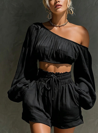 Model wearing the Women's One-Shoulder Ruched Crop Top & High-Waist Shorts Set in black, featuring a gathered one-shoulder neckline, billowy long sleeve, and high-waist drawstring shorts.