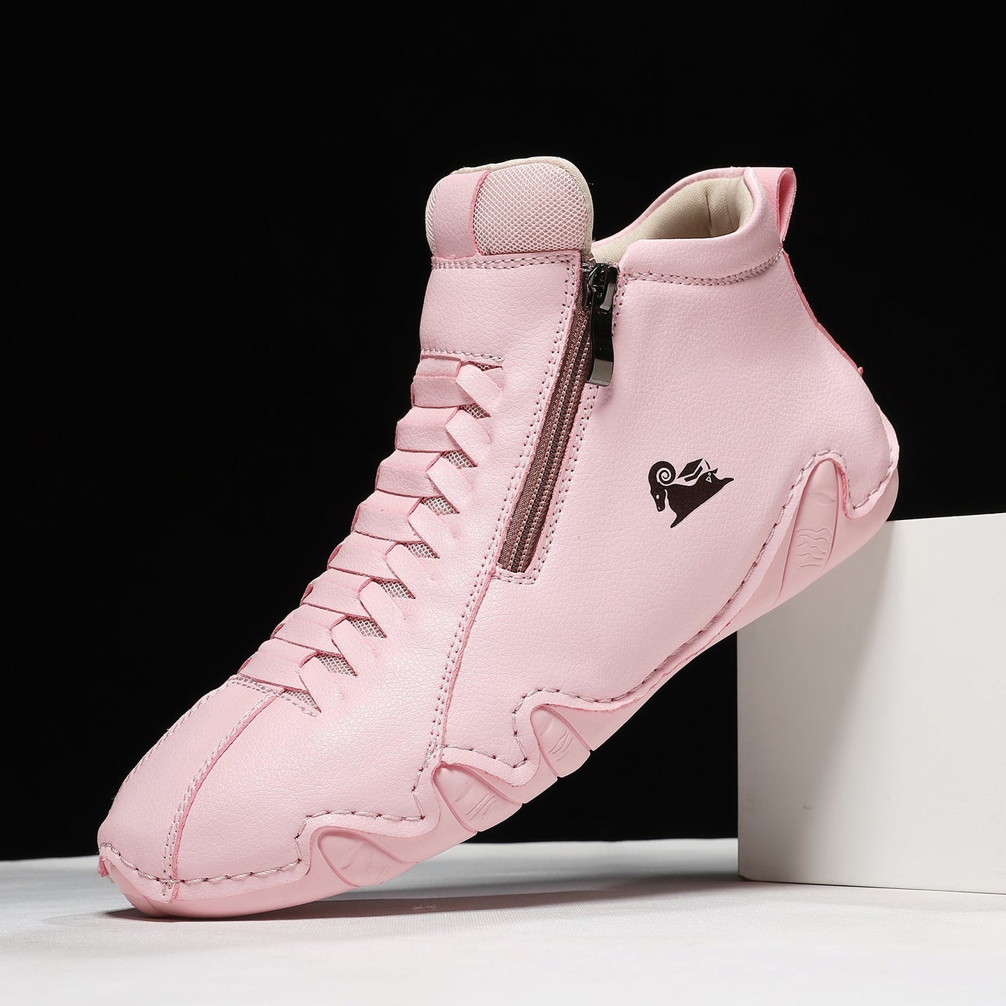 Pink high-top athletic sneaker with a textured finish, side zipper, and cushioned sole, photographed against a black and white background.