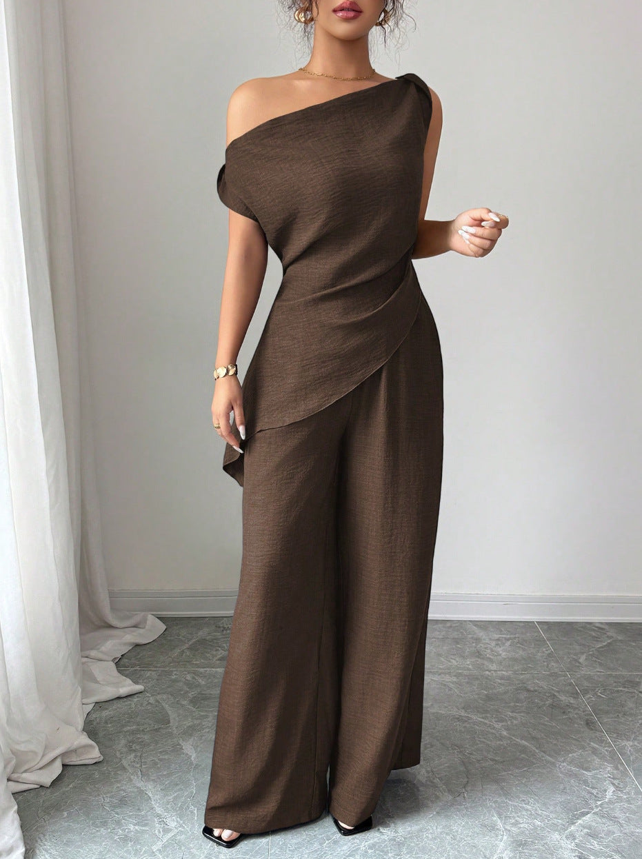 Woman wearing a dark brown casual two piece set featuring a draped one-shoulder top with a layered cross-body fold and matching high-waisted wide-leg pants.