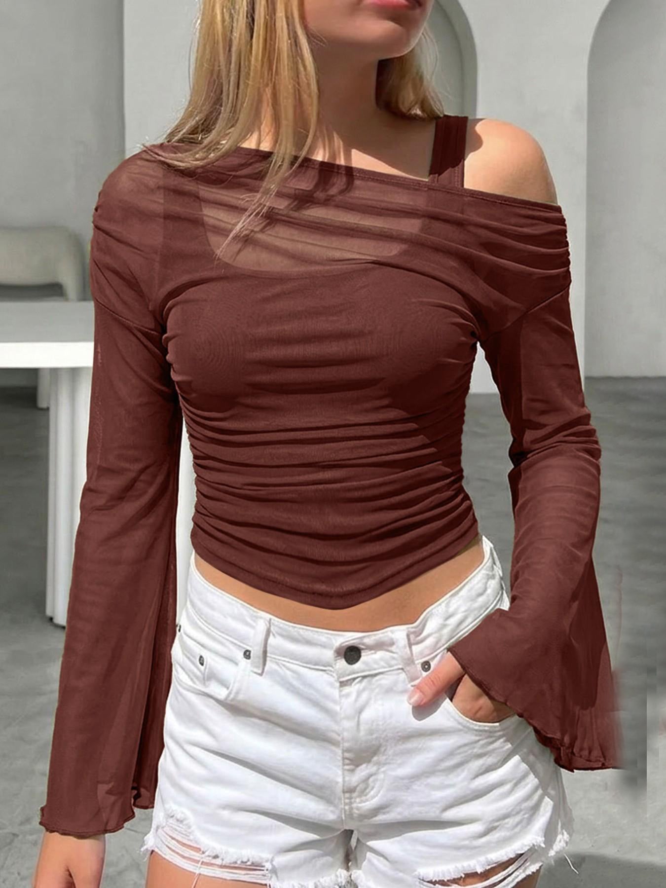A woman wearing a dark brown mesh neck long-sleeve top and white denim shorts, posing in an indoor lifestyle setting.