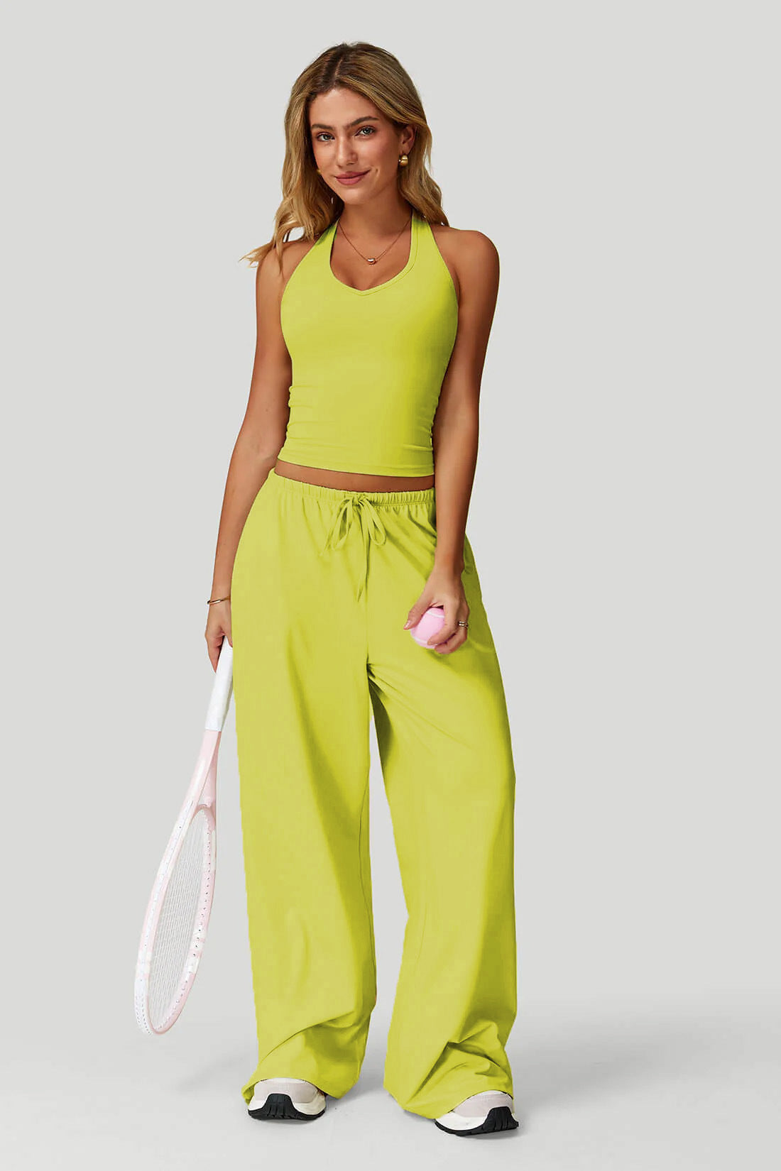 Women's sporty crop tank and wide-leg pants set in yellow, full outfit front view showing V-neck crop top, wide-leg silhouette, and tennis racket
