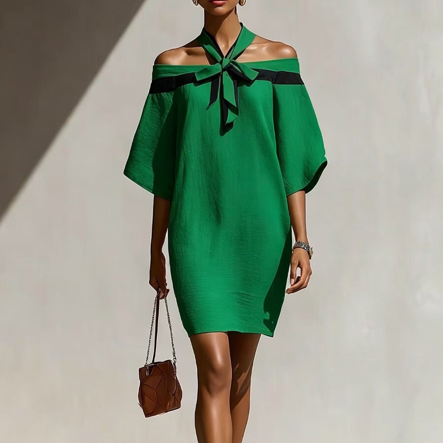 Woman wearing a green off-the-shoulder A-line mini dress with a contrasting black bow collar