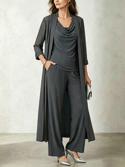 Model wearing a carbon gray three-piece cardigan and wide-leg pant set, accessorized with metallic silver pointy-toe pumps and a matching clutch.