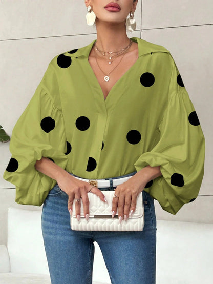 Woman wearing a matcha green polka dot V-neck long-sleeve top with bubble sleeves and blue jeans.