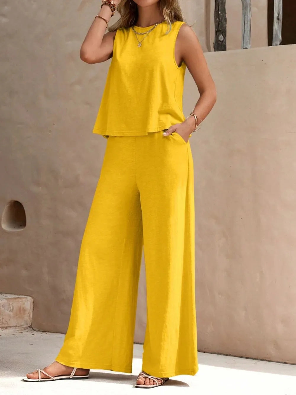 Front view of model wearing a gold yellow sleeveless round neck top and high-waisted wide leg pants set with sandals
