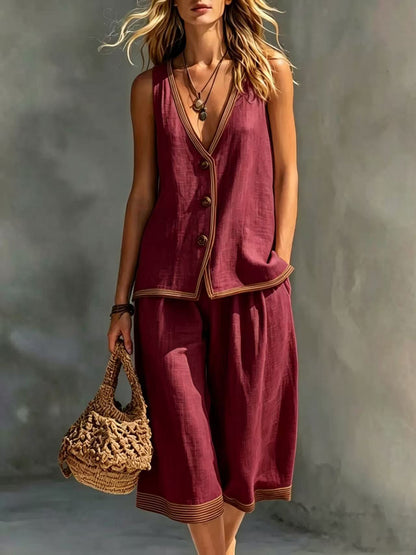 Women's wine red sleeveless buttoned vest and matching cropped wide-leg pants two-piece set featuring contrast trim detailing, modeled outdoors with a woven handbag.