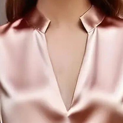 Close-up of a woman wearing a light pink satin V-neck long-sleeve blouse with a structured collar.