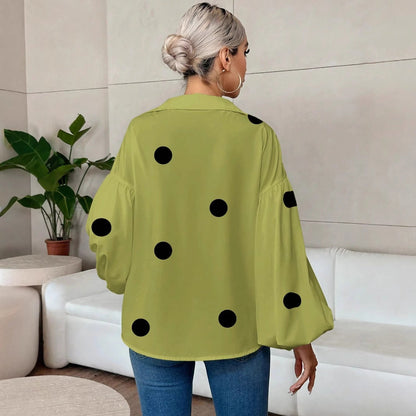 Back view showing the upper body of a blonde woman wearing a loose matcha green top with large black polka dots, featuring a collared back and wide bubble sleeves, paired with blue jeans.