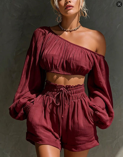 Model wearing the Women's One-Shoulder Ruched Crop Top & High-Waist Shorts Set in burgundy, featuring a gathered one-shoulder neckline, billowy long sleeve, and high-waist drawstring shorts