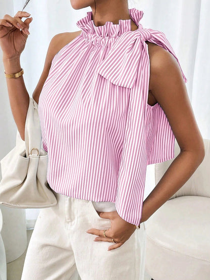 Close-up view of a model wearing a striped sleeveless top featuring a ruffled high neck, lace trim, and side tie-knot bow.