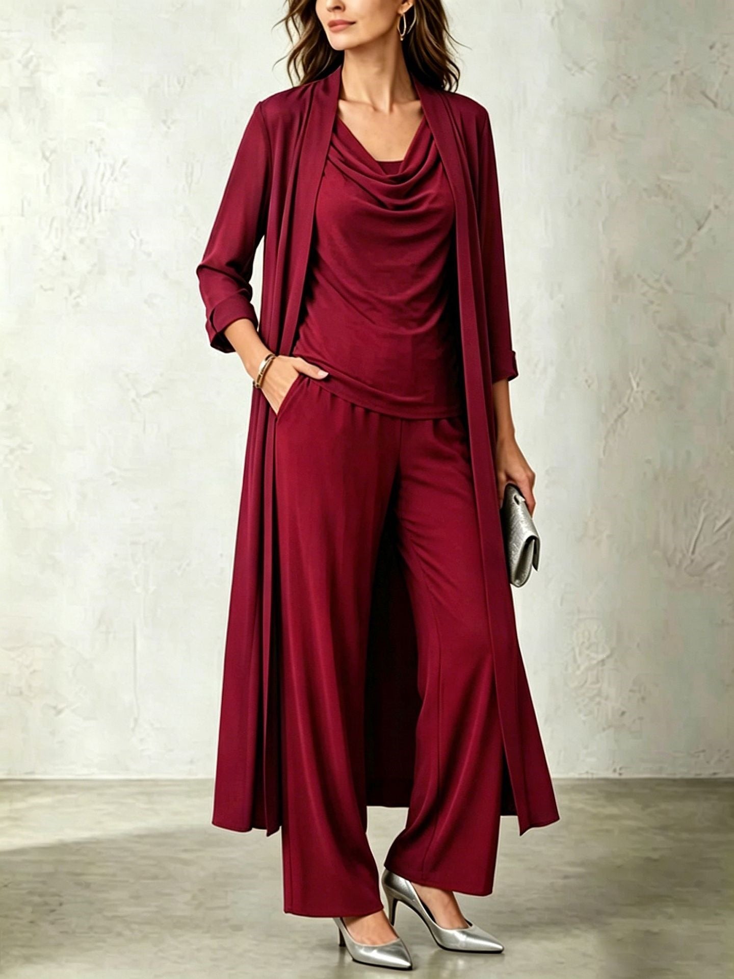 Model wearing a rich burgundy three-piece cardigan and pant set paired with silver metallic pumps and a silver clutch.