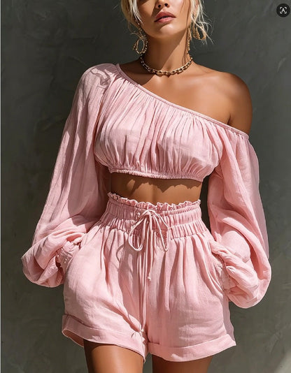 Close-up view of the women's one-shoulder ruched crop top and high-waist drawstring shorts set in pink, highlighting the gathered neckline and billowy sleeve styling.