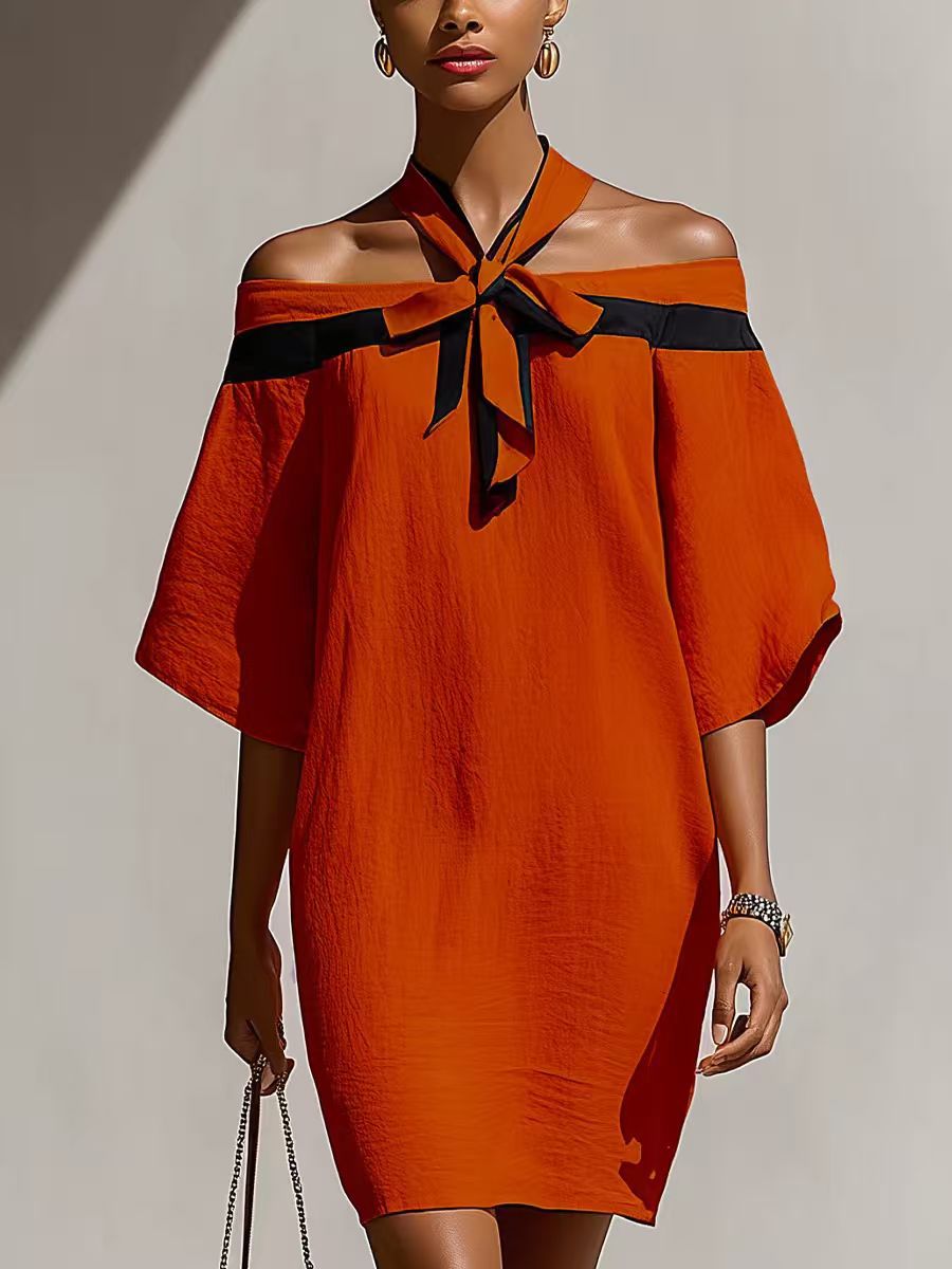 Woman wearing an orange-red off-the-shoulder A-line mini dress with a contrasting black bow collar