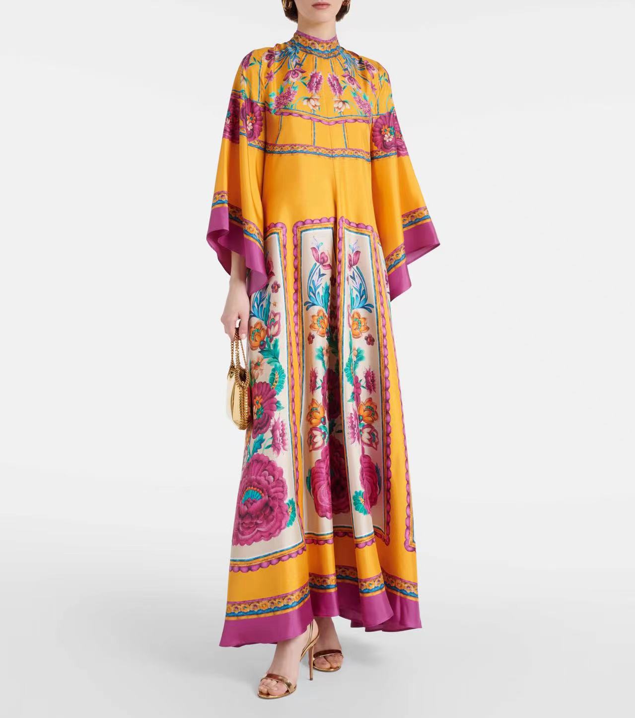 Women's floor-length A-line maxi dress in vibrant mustard yellow featuring a magenta and turquoise floral motif print, high mock stand collar, wide 3/4 flared sleeves, and decorative magenta border trim.