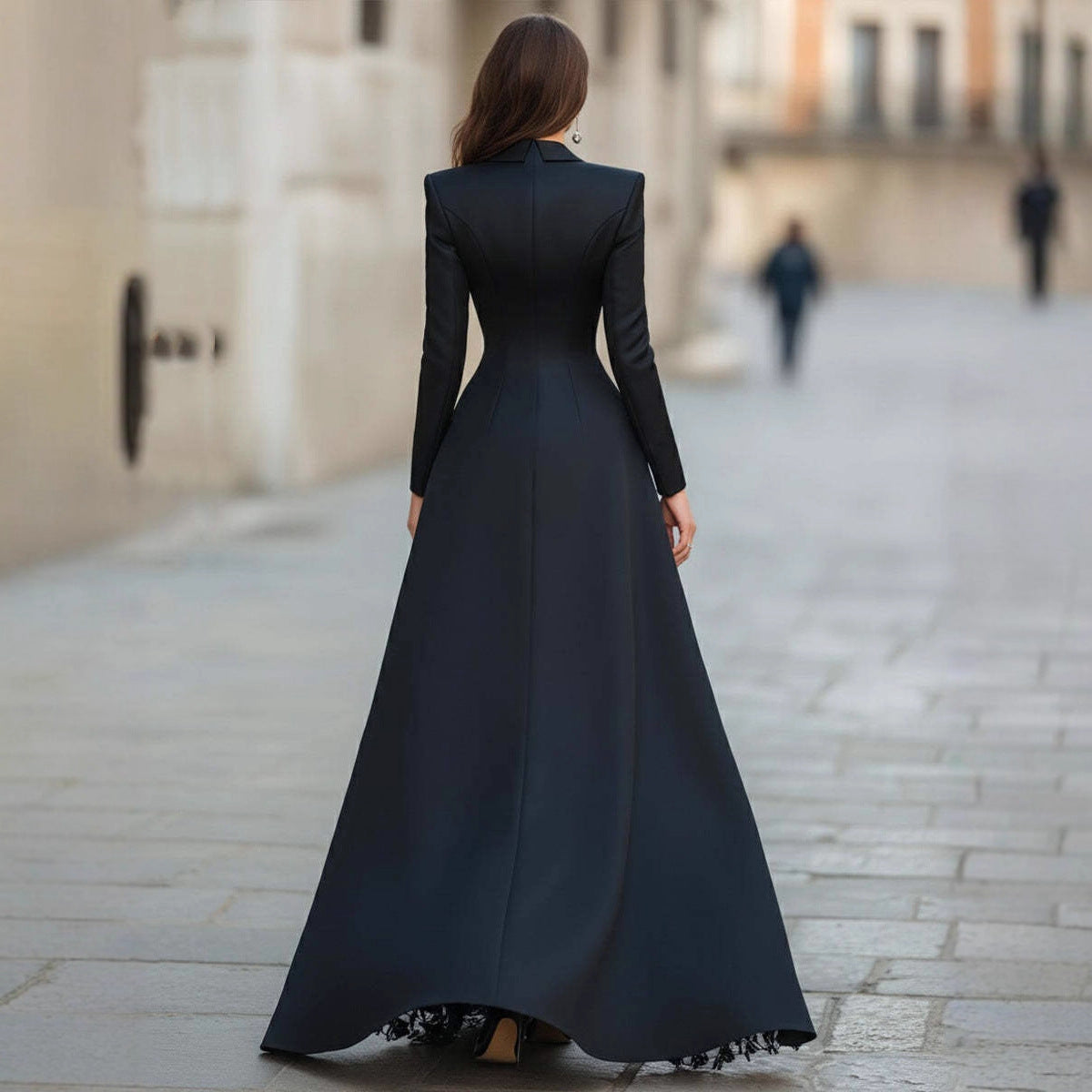 Rear view of a women's elegant black formal outfit featuring a structured long-sleeve jacket top with padded shoulders and a floor-length A-line skirt.