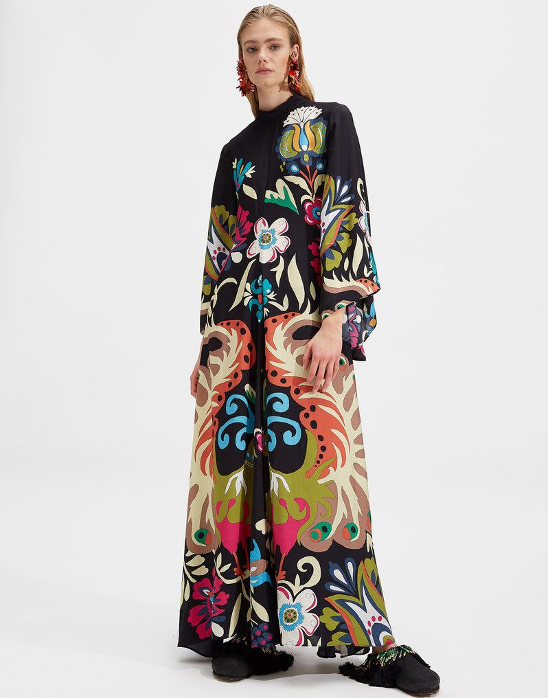 Women's floor-length A-line maxi dress in black featuring a vibrant, colorful botanical floral print, high mock stand collar, and dramatic wide 3/4 flared sleeves.