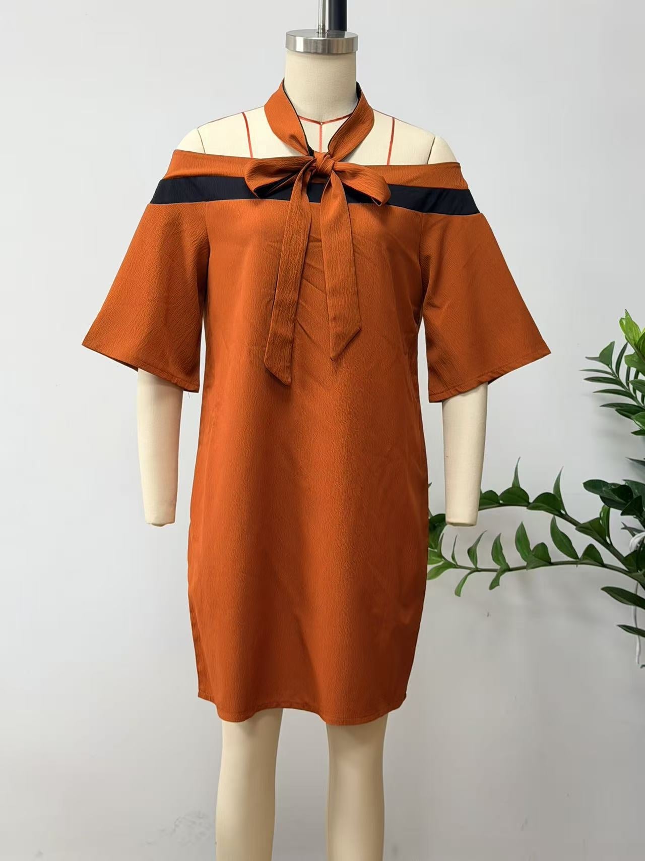 Orange-red off-the-shoulder A-line mini dress with a black bow collar detail on a mannequin