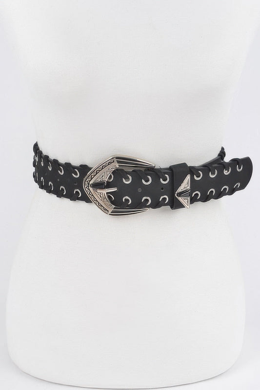 Close-up detail of a wide black belt with double metal eyelets and a decorative Western-style carved buckle, displayed on a white dress form.