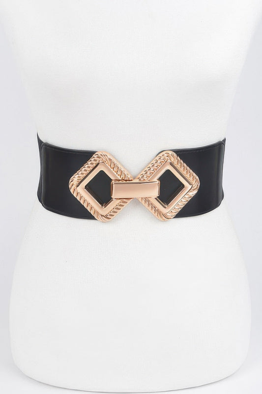 Front view of a wide black elastic stretch belt featuring a textured gold-tone interlocking geometric buckle, styled on a white dress mannequin against a light background.
