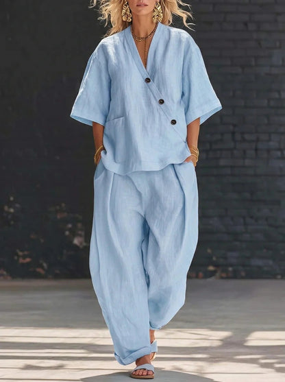 Light blue V-neck short sleeve top and high-waist trousers two-piece set featuring a relaxed fit, button accents on the top, and full-length wide trousers.