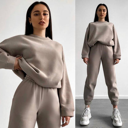 Woman wearing a beige loose-fit crewneck sweatshirt and matching jogger pants two-piece set, styled with white sneakers.
