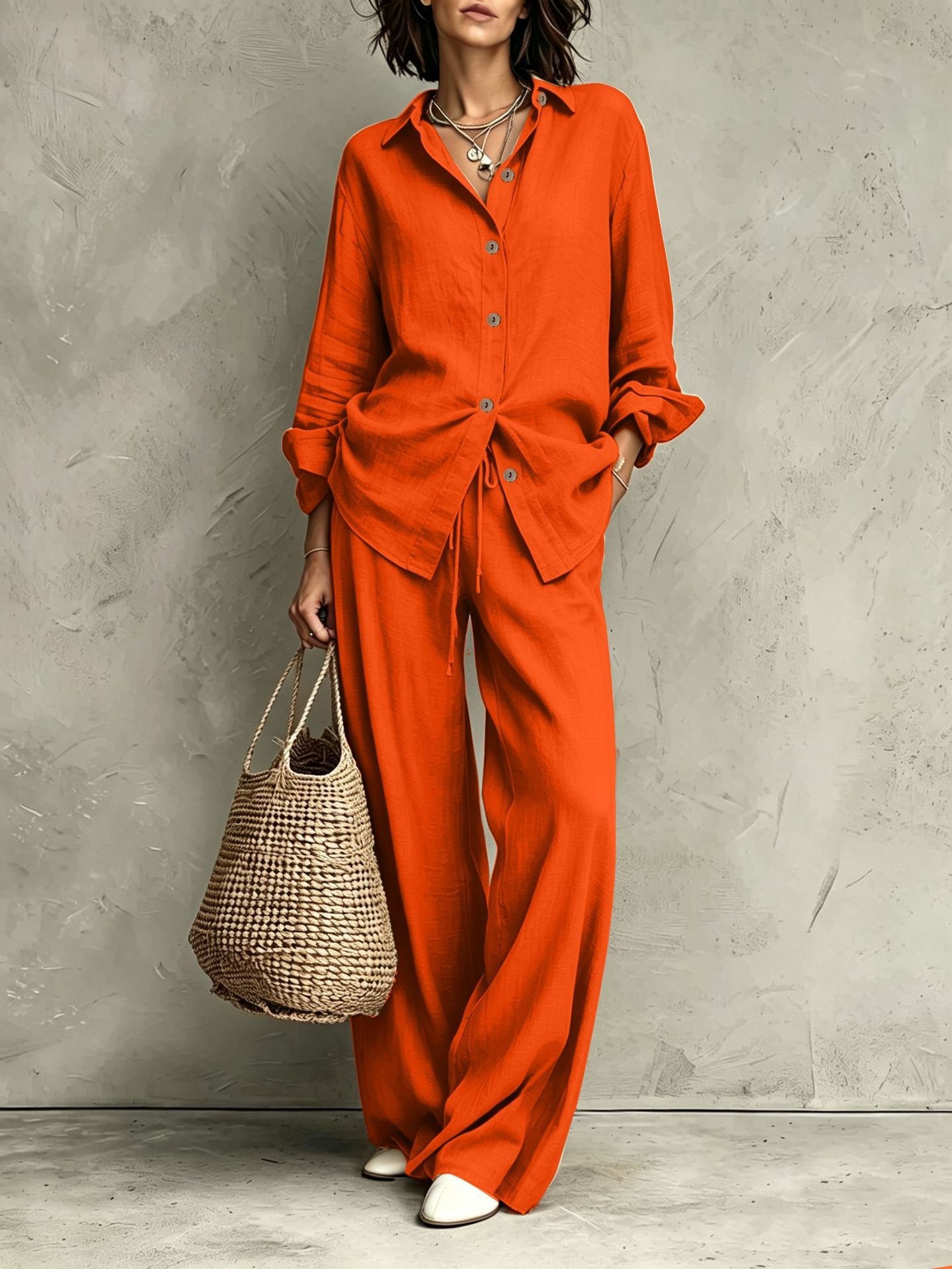 Women's button-down shirt and wide-leg pants set in orange-red – full outfit front view showing relaxed casual silhouette and straw bag