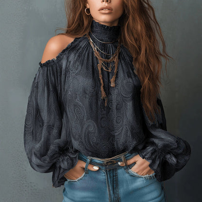 Front view of a woman wearing a black retro cashew print off-shoulder blouse with dramatic lantern sleeves and a high neckline, styled with denim jeans.