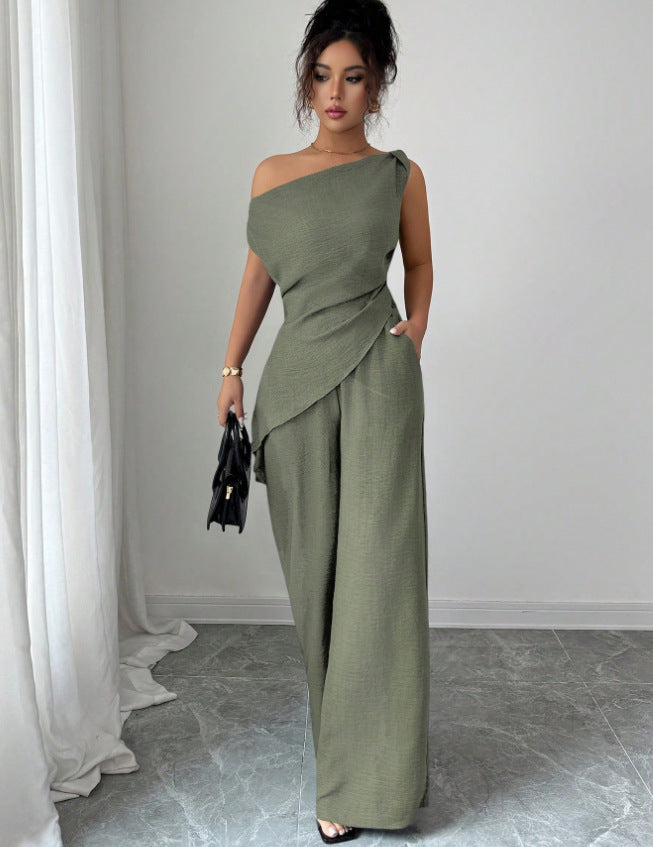 Woman wearing an olive green casual two piece set featuring a draped off-the-shoulder top with a layered cross-body fold and matching high-waisted wide-leg pants, holding a black handbag.