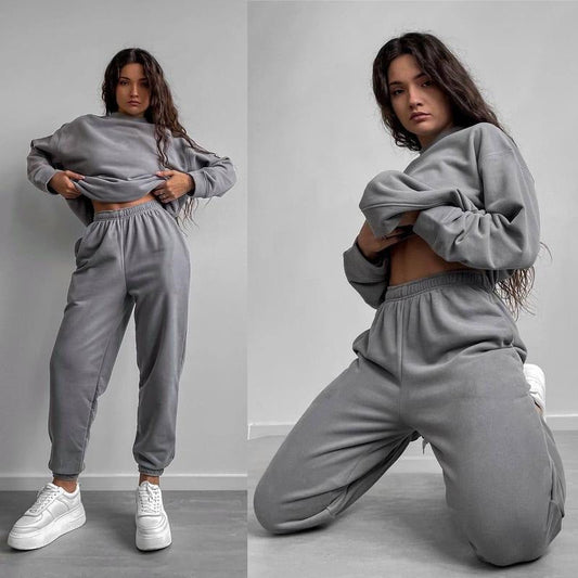 Woman wearing a gray loose-fit crewneck sweatshirt and matching jogger pants two-piece set, styled with white sneakers.